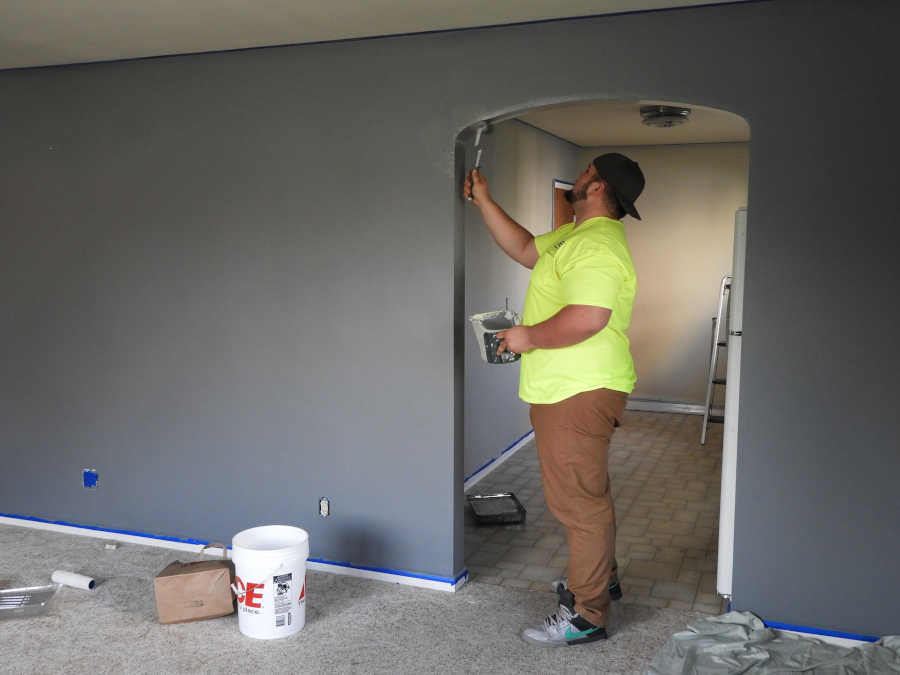 image-of-a-professional-painter-painting-a-wall-using-brush-and-holding-a-paint-mug-in-his-hand.